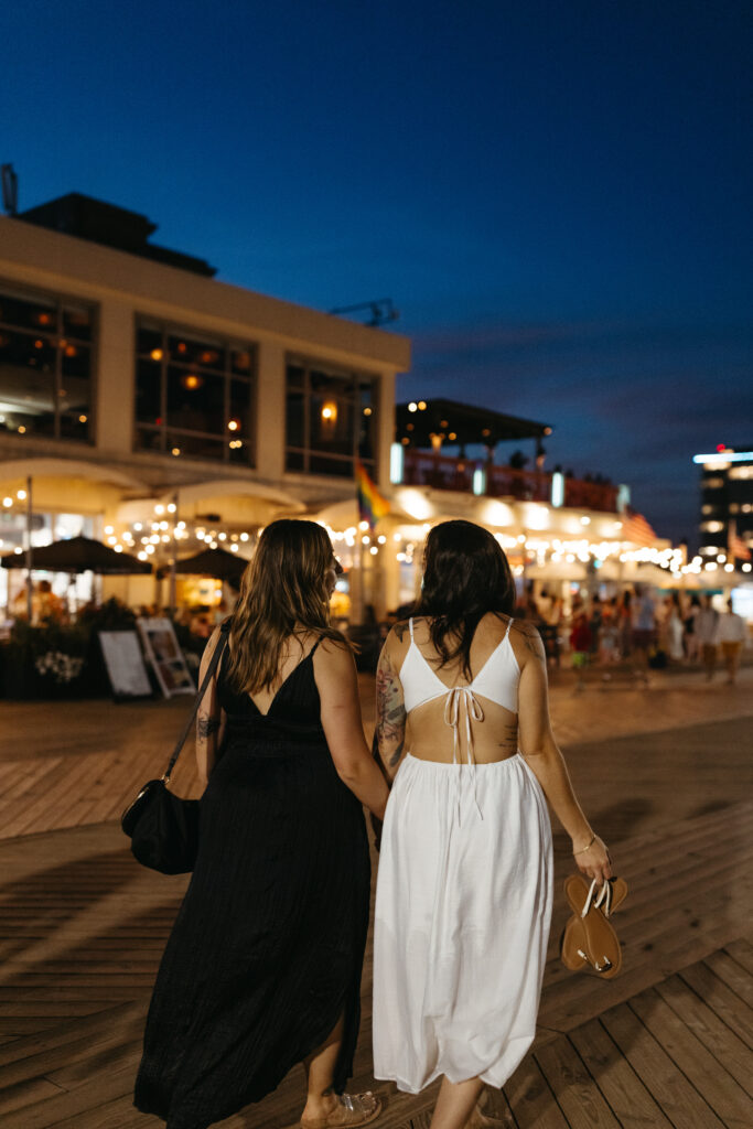 Couple walking along Asbury Park boardwalk holding hands at night