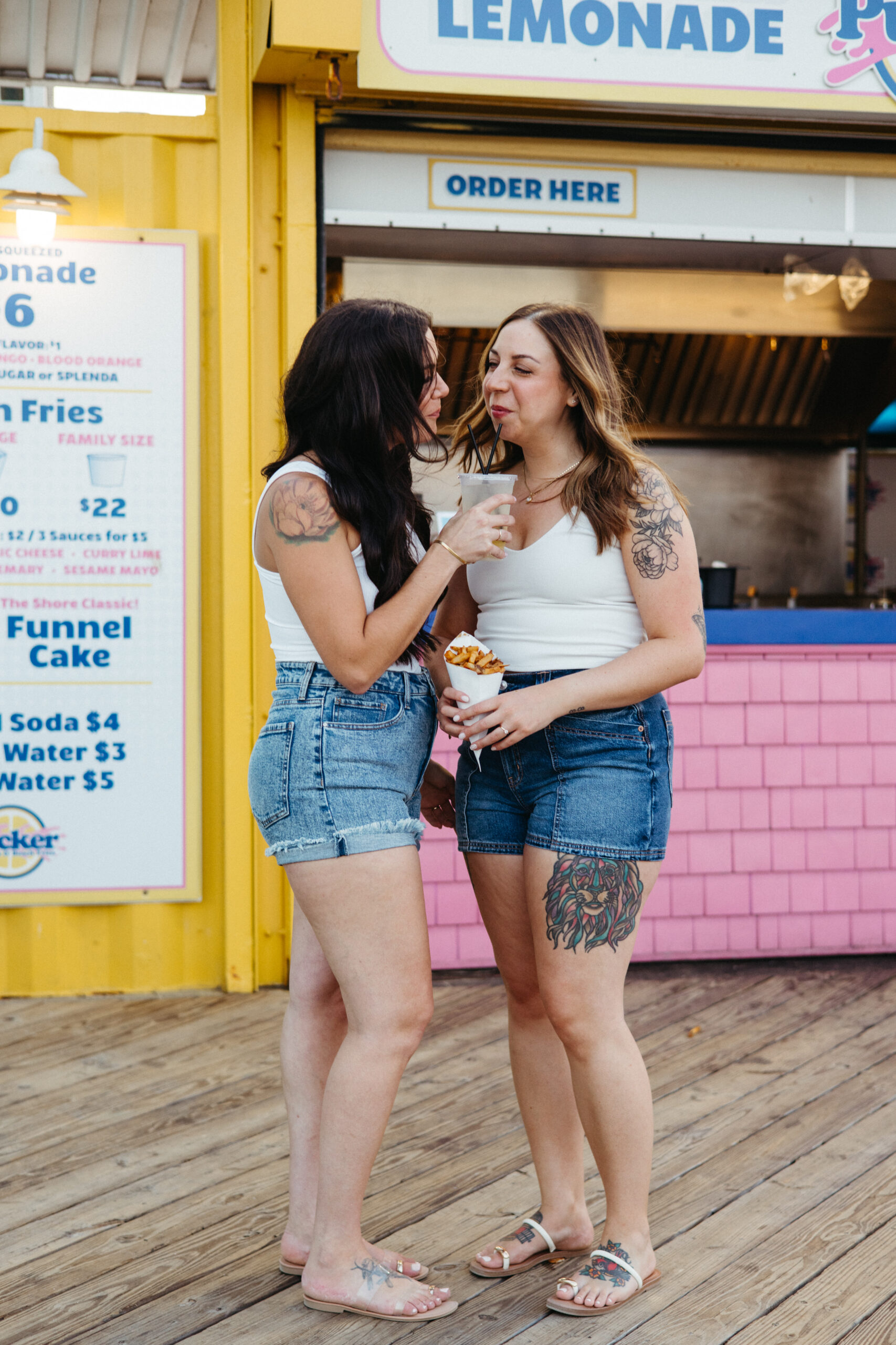 rainbow couple walking along Asbury Park boardwalk holding hands